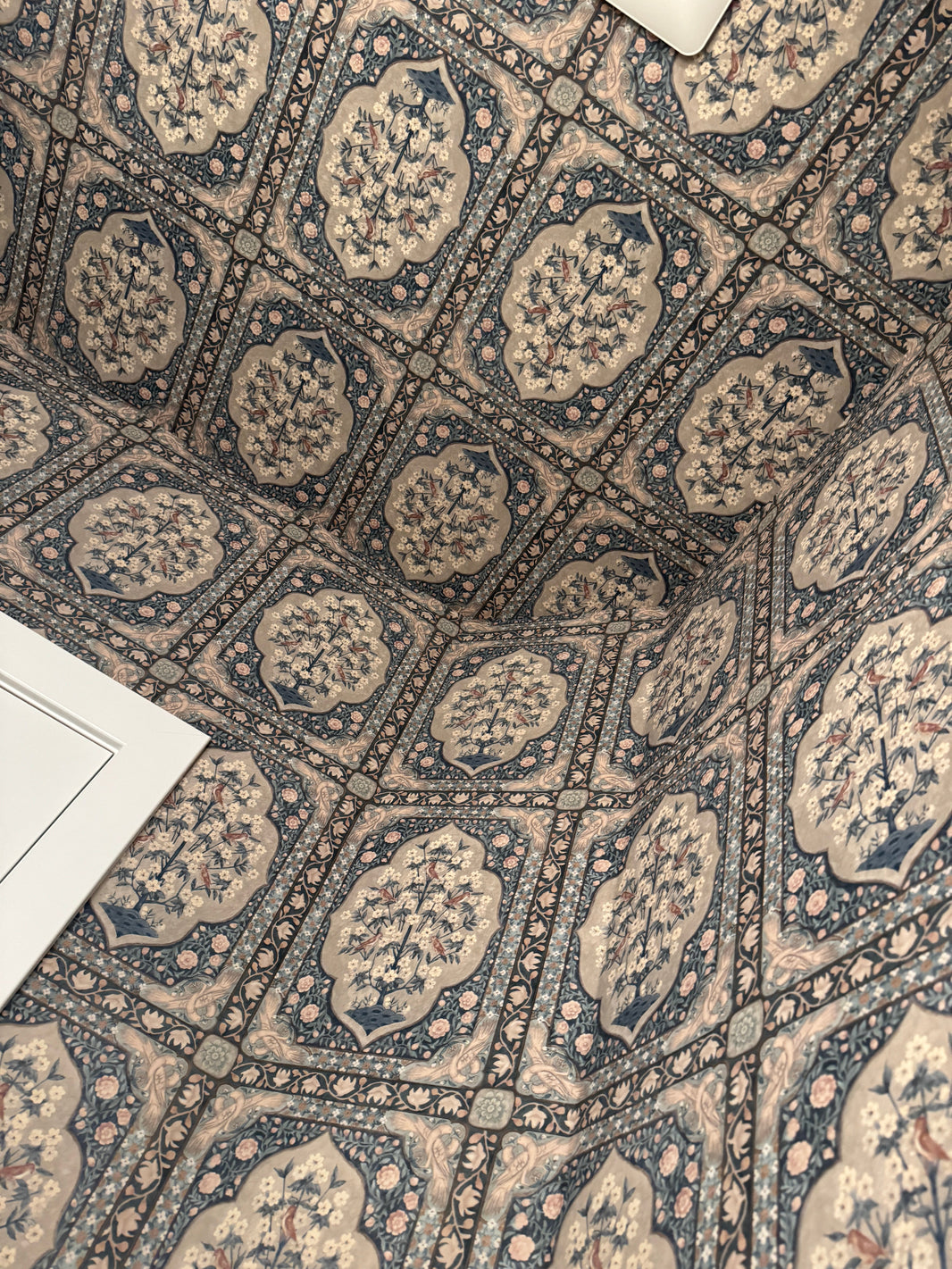 Detail: wallpapered ceiling draws the eye up; pattern meets white tile wainscot cleanly Ceiling close-up: large-scale pattern overhead adding height and drama in a small bathroom
