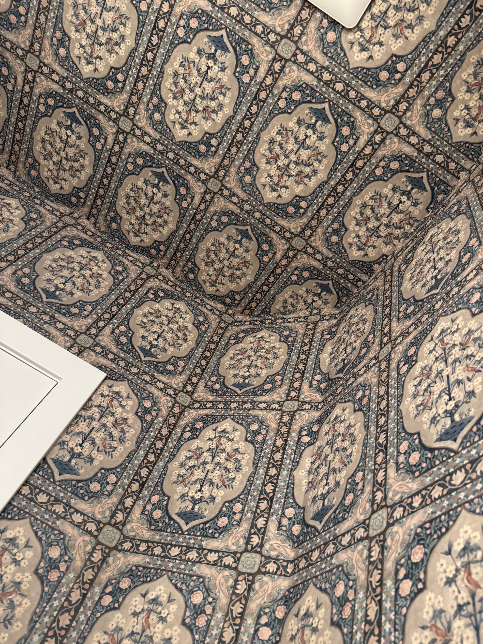 Detail: wallpapered ceiling draws the eye up; pattern meets white tile wainscot cleanly Ceiling close-up: large-scale pattern overhead adding height and drama in a small bathroom