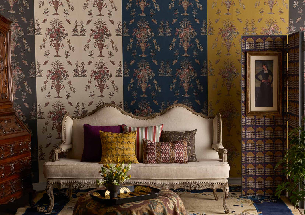 Coromandel Garden wallpaper hung in alternating colourways behind a carved settee, with a Khiva Raindrop screen