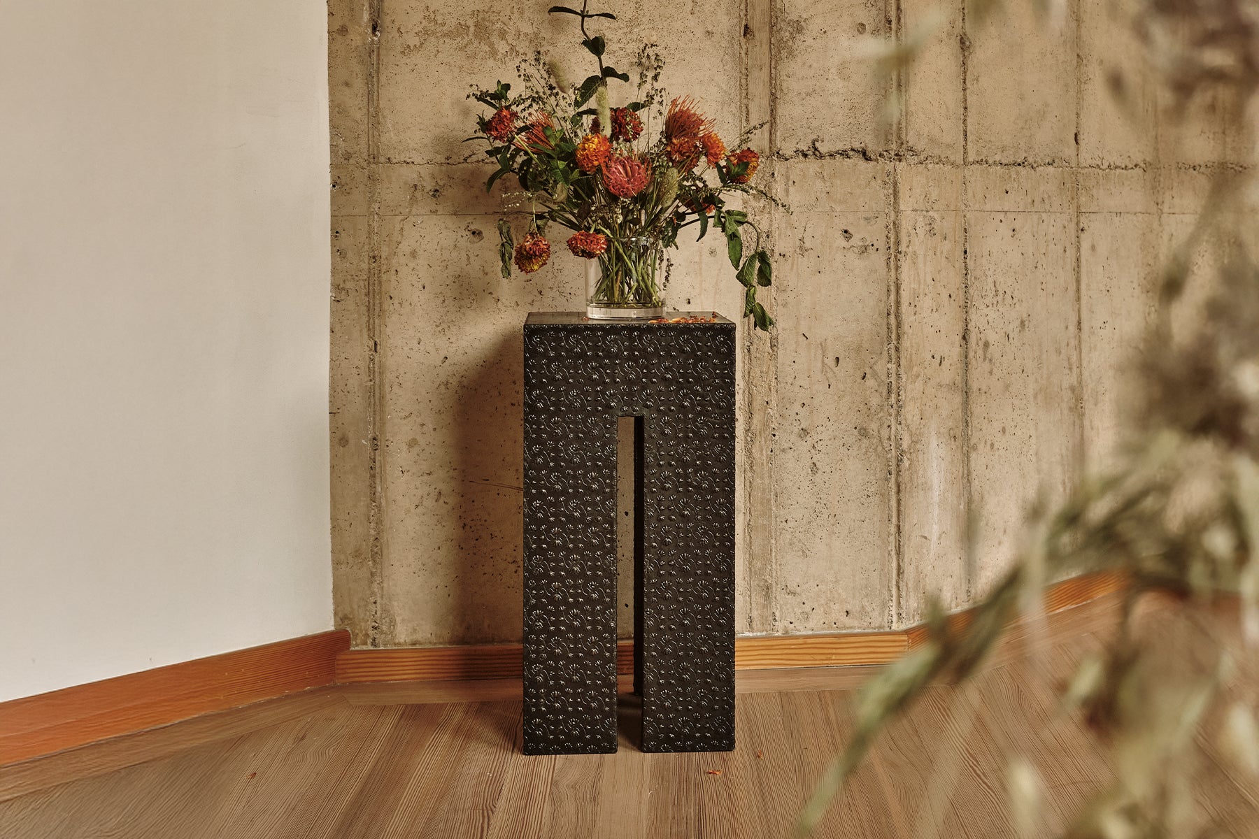 Handcrafted embossed black metal Z-table with repetitive floral motifs, front view.